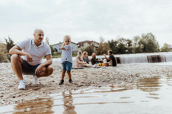 Foto eines Mannes mit Kind am Ufer der Erlauf