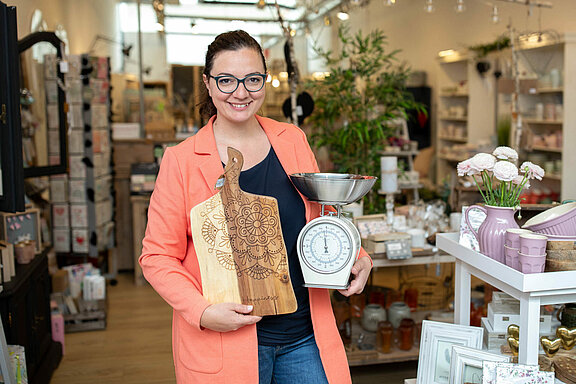 Mitarbeiterin mit Waage und Holzbrett in den Händen 