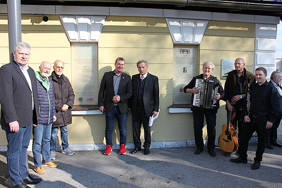 Eine Auswahl der Ehrengäste und die Musikanten vor den beiden Gedenktafeln.