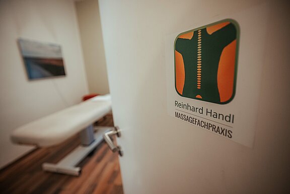 Eingangstür zur Massagefachpraxis, auf der Tür ist das Logo sichtbar 
