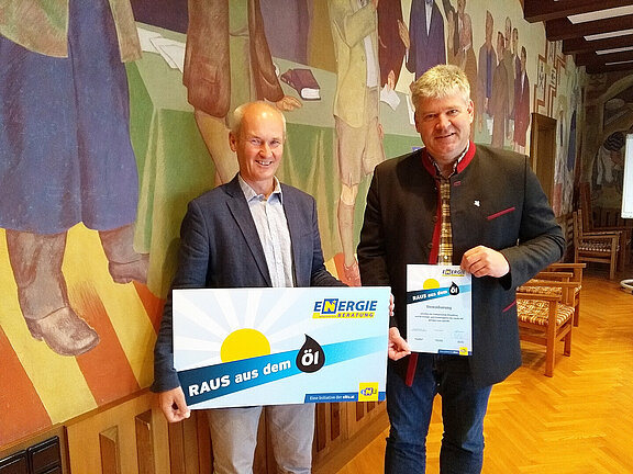 Bürgermeister Josef Leitner und Johann Wagner von der Energie- und Umweltagentur des Landes NÖ im Sitzungssaal des Rathauses mit der Vereinbarungsurkunde und einem Schild zum Thema "Raus aus dem Öl"