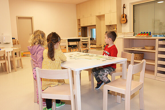 Drei Kinder spielen an einem Tisch im neuen Kindergarten.