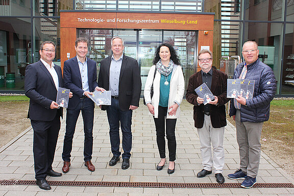 Das Organisationsteam mit DI Klaus Nagelhofer, Stadtamtsdirektor Franz Willatschek, DI Dr. Gernot Zweytick, Renate Laube von der Stadtgemeinde Wieselburg, Mag. Johannes Distelberger und Stadtrat Josef Lechner steht vor dem Haupteingang des Technologie- und Forschungszentrums Wieselburg-Land und präsentiert das frisch gedruckte Vorlesungsverzeichnis. 