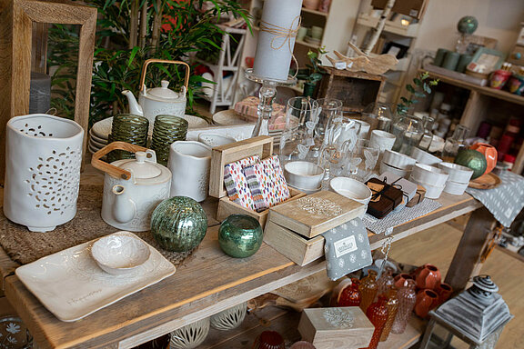 Geschirr, Wohntextilien und Windlichter auf einem Tisch 