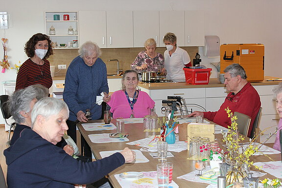 Gäste des Tagesbetreuungszentrum bereiten sich mit Unterstützung des Pflegepersonals im Essbereich bzw. der Küche auf das Mittagessen vor.